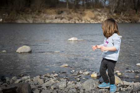 Toddler baby girl playing on the rocky river beach. Rivergaro, Val Trebbia, Italy.の写真素材
