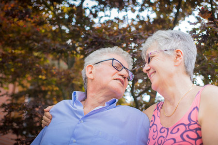Portrait of an old couple, smiling at each other with loving expression in outdoor scenery