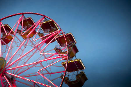 Colorful ferris wheel at dusk, illuminated by red neon lights. Background with copy space. Rosolina Mare amusement park, Veneto, Italy.のeditorial素材