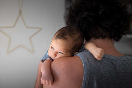 Young, caucasian father, back view, holding newborn baby on his shoulder.の写真素材