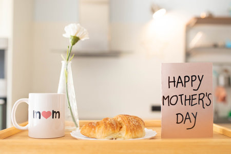 Mother's day still life with mom cup, a sweet pastry and a greeting card on a tray, in airy indoor...