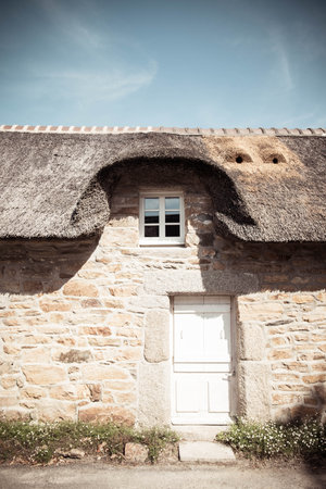 Detail of a traditional thatched roof cottage house in the charming Village of Kercarnic, Brittany (Bretagne), France. Vertical shot.の写真素材