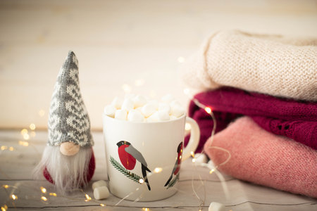 Christmas still life with robin cup filled with chocolate and marshmallows, gnome doll and string...