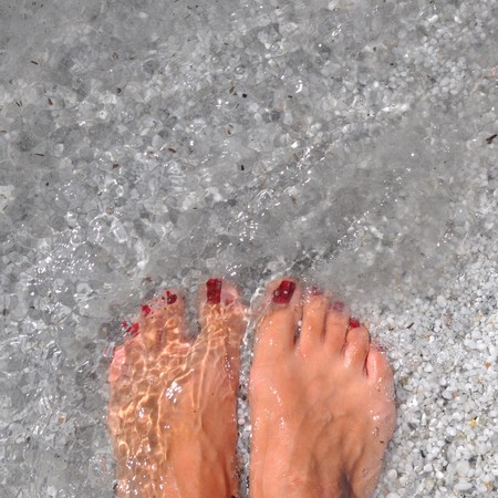 Female feet in blue water at seaの写真素材