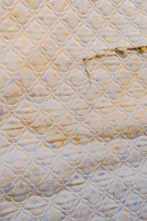 Old torn mattress pad for sleeping on a bedの写真素材