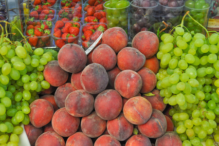 Many fruits including peach uve strawberry on a supermarket shelfの写真素材