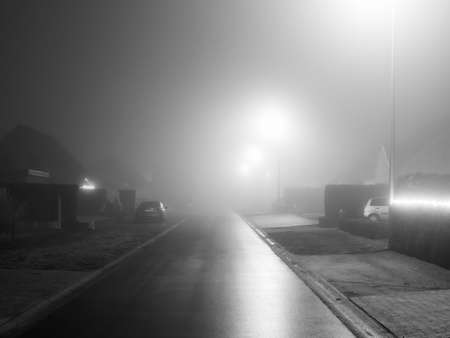 Black and white photo of a street in a foggy night.の写真素材