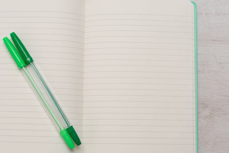 open-ended notebook with no text and two green pens