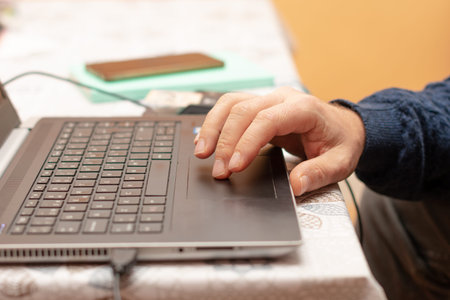 middle-aged man's hand using the laptop to work from home in the morning