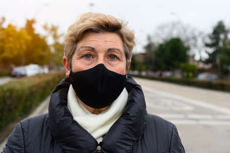 portrait of elderly woman serious with face mask in the streetの写真素材