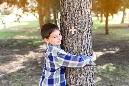 Happy child hugging a tree trunk in a forest. Concept of caring for the environmentの写真素材