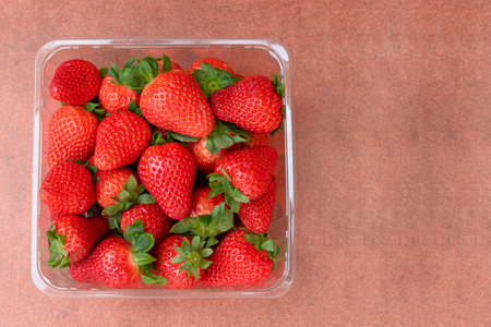 Bowl full of strawberries on brown background