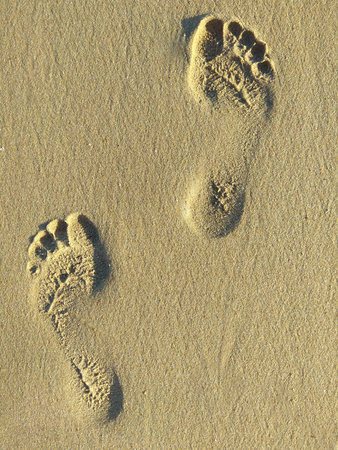 Two barefoot human footprints on the beach sand