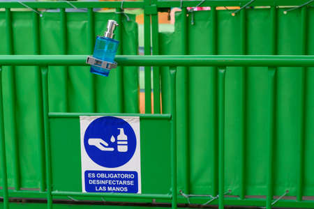 Green billboard with a bottle of hydroalcoholic gel and a sign that says in Spanish "It is mandatory to disinfect hands"の写真素材