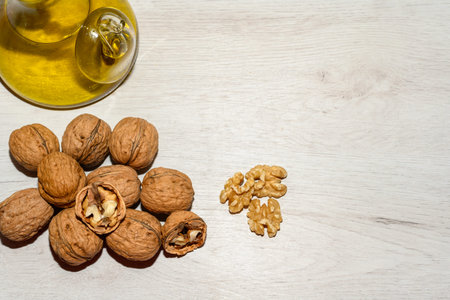 Lots of walnuts, some peeled, along with a small jar of oil. View from above with copy space