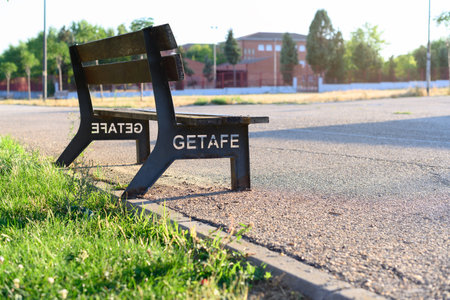 Park bench with Spanish lettering that reads Getafe. Which is a town in Madrid in Spain. In the...