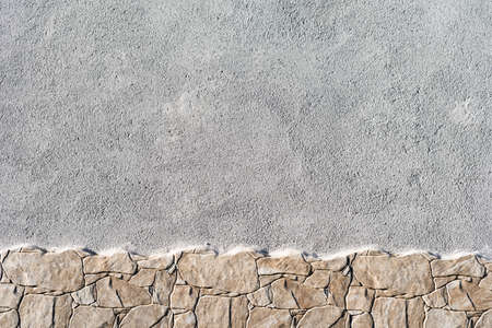 Wall background painted in gray and bottom border with light brown stonesの写真素材