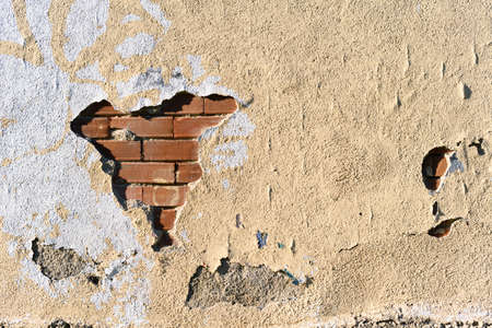 Background of yellow painted wall, aged, in ruins with brick partsの写真素材