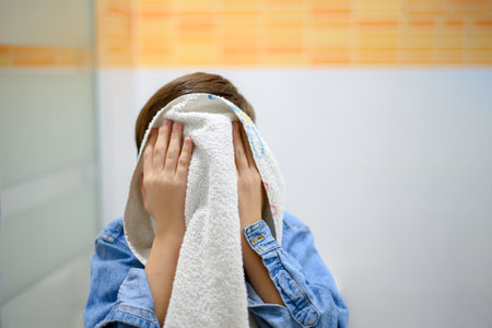Unrecognizable child close up drying his face with a towelの写真素材