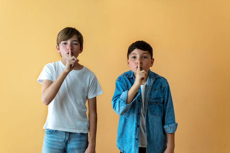 Two children put their index fingers in their mouths. Silence conceptの写真素材