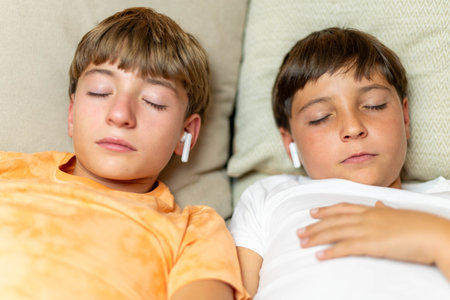 Close-up portrait of two relaxed children sleeping with headphonesの写真素材