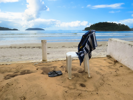View of the quiet and deserted beach in sunny day, with a chair and a towel.の写真素材