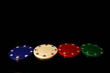 Four color casino chips arranged straight isolated on blackの写真素材