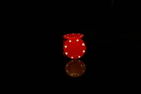 Red chips stack with a red chip in front isolated on black with reflectionの写真素材