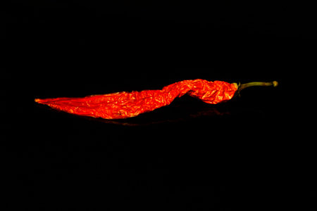 Red chilli isolated on black with reflection