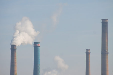 Furnaces with white smoke on blue sky close-up polluting the atmosphere