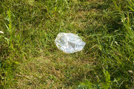 Plastic bag polluting grass close-up view with selective focus on foregroundの写真素材