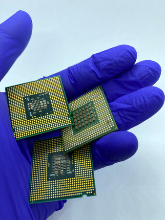 Three microprocessors kept in hand covered by glove close-up view isolated on white background