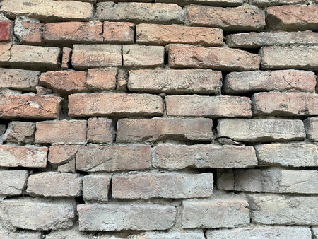 Close-up of grey red old brick of different sizes with cracks and selective focus on foreground