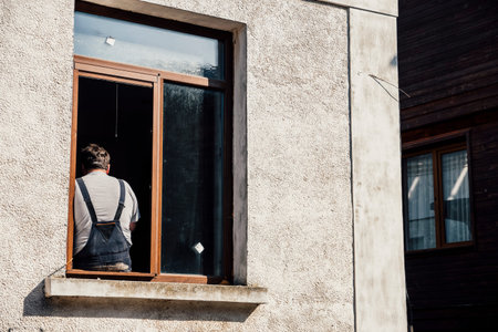 A male worker has a break from work sitting on the edge of a window.