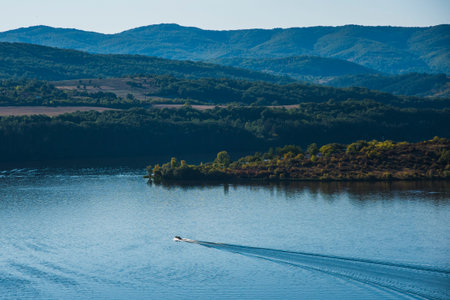 A boat speeding through a lake. A lake, sea, coast between mountains, rocks, nature in Bulgaria. Beautiful sunny day. High quality photoの写真素材