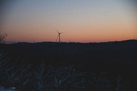 Wind turbine on sunset. Sunset landscape with snow in winter. Orange skies, golden hour in Bulgaria.の写真素材