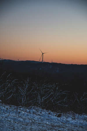 Wind turbine on sunset. Sunset landscape with snow in winter. Orange skies, golden hour in Bulgaria.の写真素材