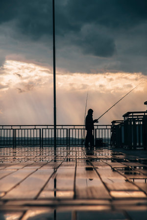 Sunset on a sea bridge after rain in Bulgaria. Reflections on ground. Amazing sea landscape. Fisherman waiting for fish.の写真素材