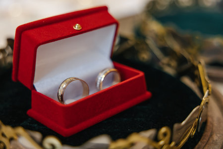 Wedding golden rings bands in a red velvet box in the center of a golden crown.