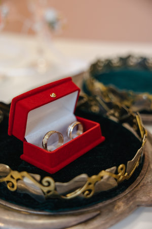 Wedding golden rings bands in a red velvet box in the center of a golden crown.の写真素材