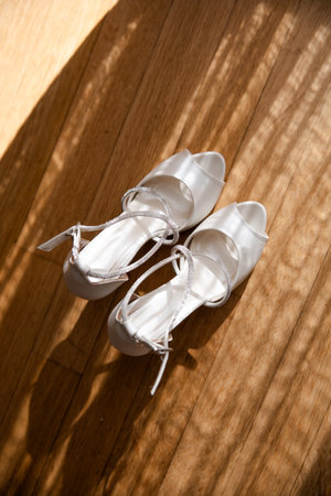 Brides wedding white shoes on the floor. Beautiful light comes through the curtain window. . High quality photoの写真素材