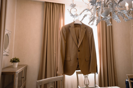Brown beige jacket hangs on white chandelier. Warm room wedding suite. High quality photoの写真素材