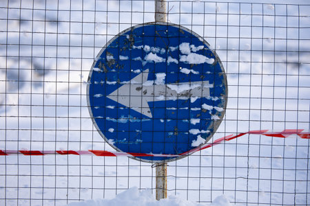 Regulatory sign with snow, proceed in direction indicated by arrow traffic sign behind a metal...