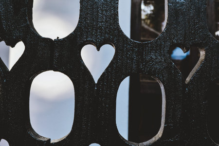 A metal fence with hearts carved into it
