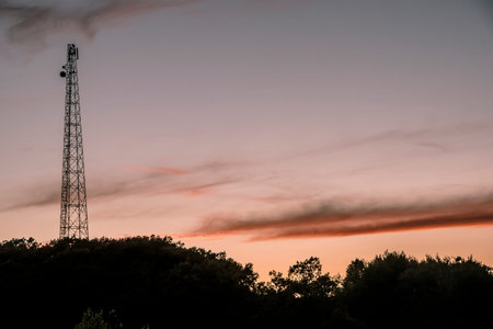 Electric pole at sunset. Golden hour. Orange sky with clouds.