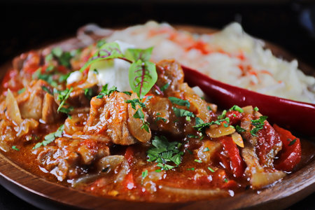 Pork stewed with vegetables and rice on a wooden plate.の写真素材