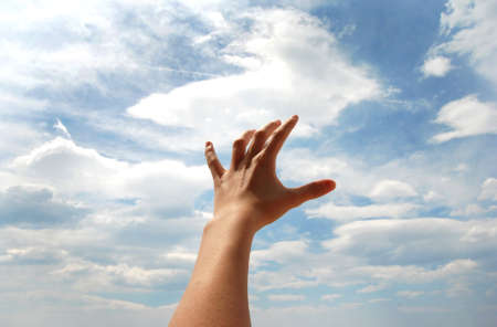 Open hand over blue sky and white cloudsの写真素材