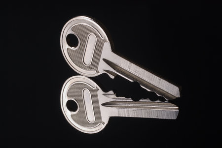 Shiny metal key with reflex on mirror isolated on black