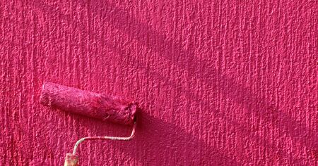 Painting of red wall with paint rollerの写真素材