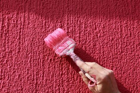 Painting of red wall with paint brushの写真素材
